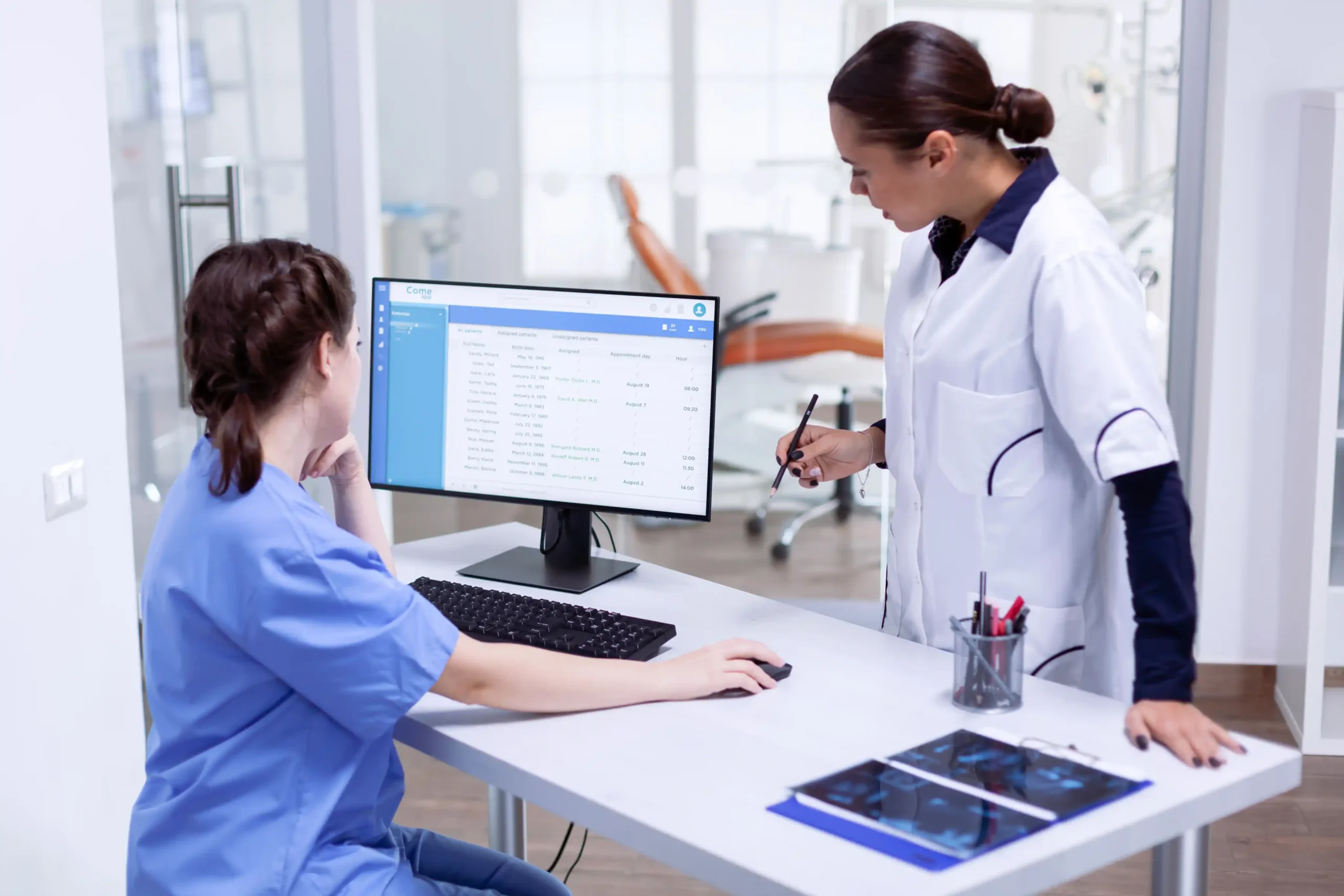 Occupational therapy staff reviewing patient records at a clinic workstation