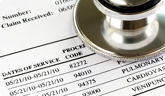 A claim form listing CPT codes and dates of service beside a stethoscope