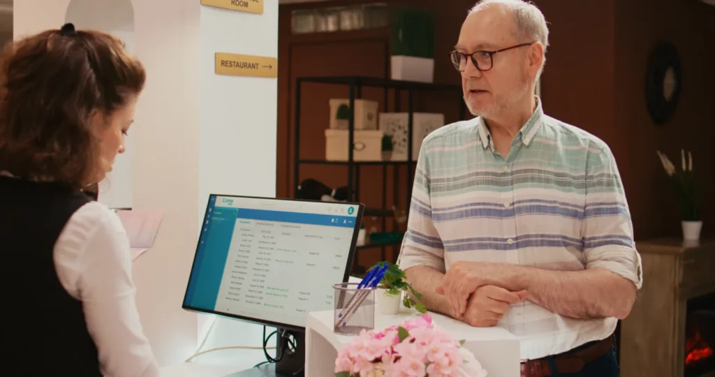 Front desk staff member checking an older patient in and verifying his coverage