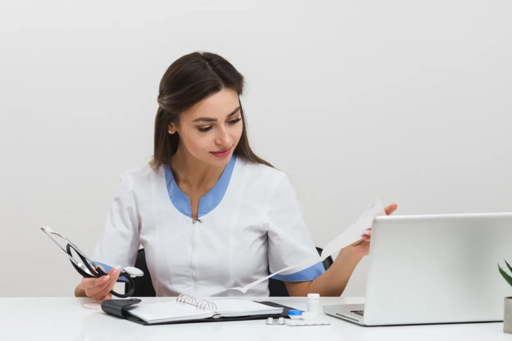Clinician reading a printed remittance report beside a laptop