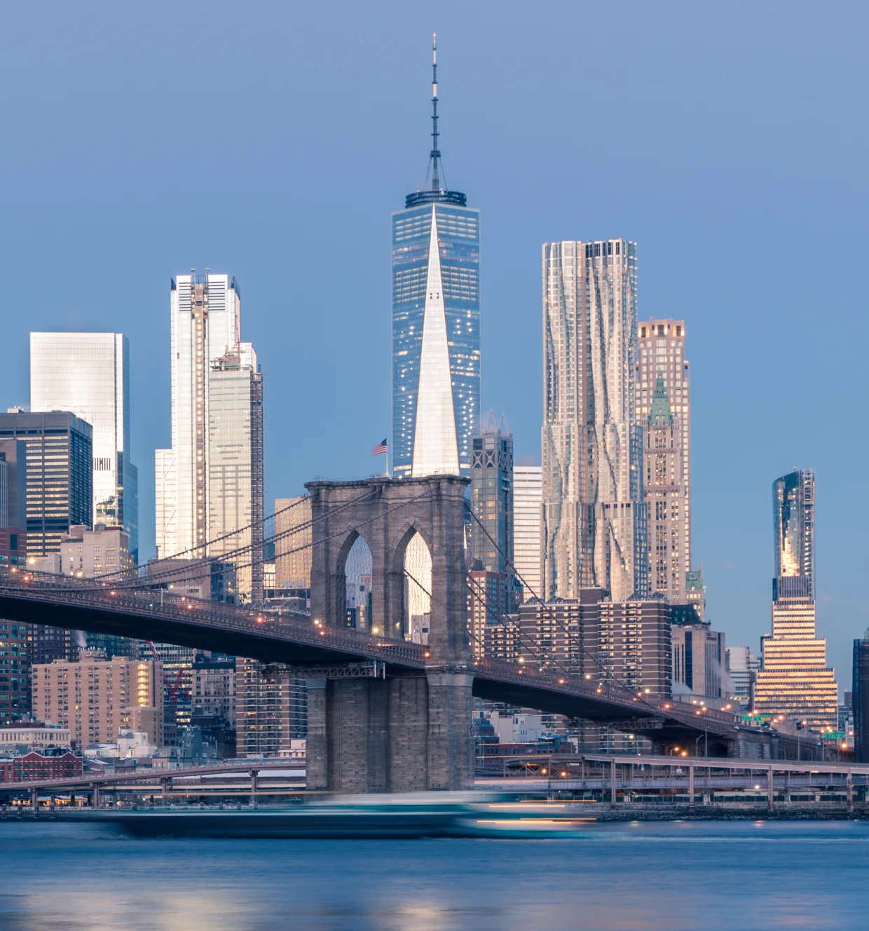 The Lower Manhattan skyline and the Brooklyn Bridge seen across the East River at dusk