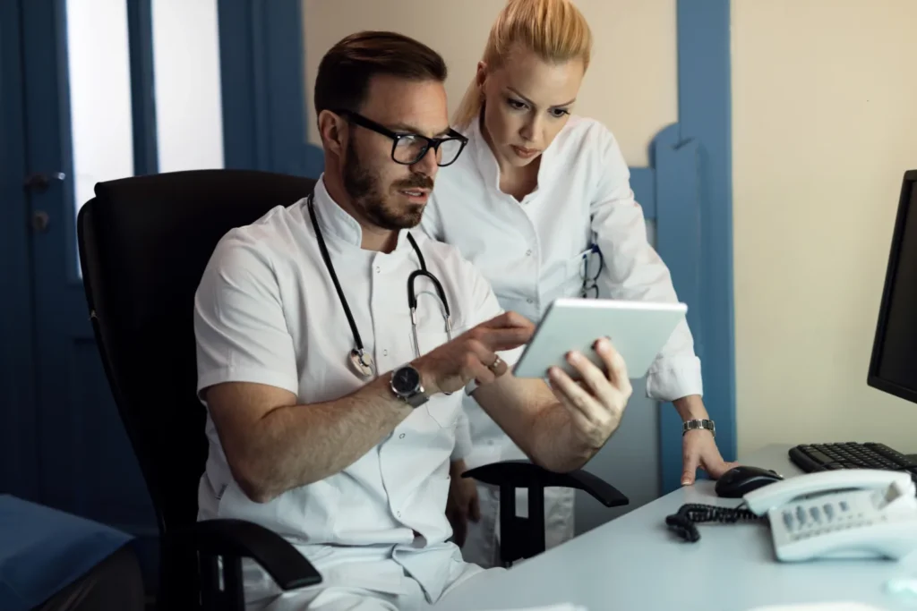 A physician and a nurse reviewing an electronic patient record together on a tablet