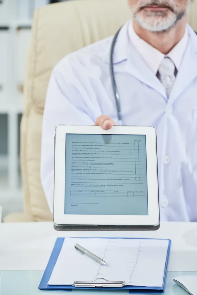 Pediatric clinician holding a tablet showing a patient coverage record