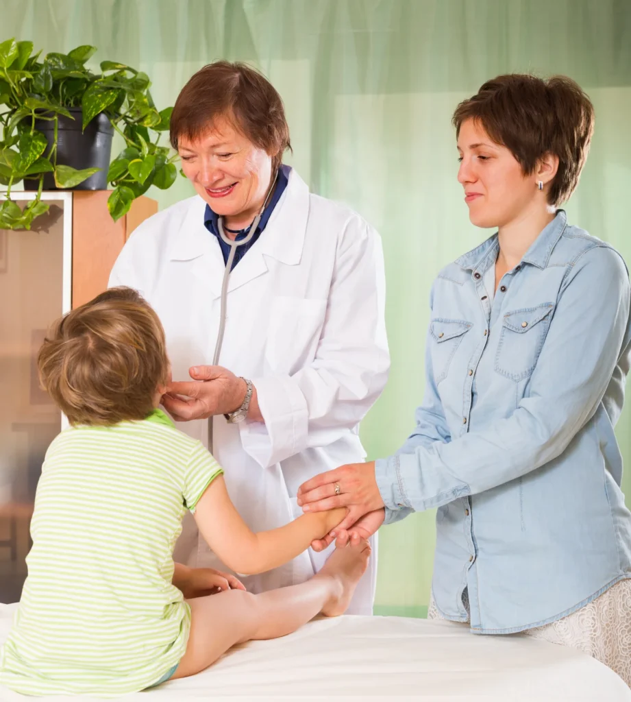 Pediatrician examining a young child while a parent looks on