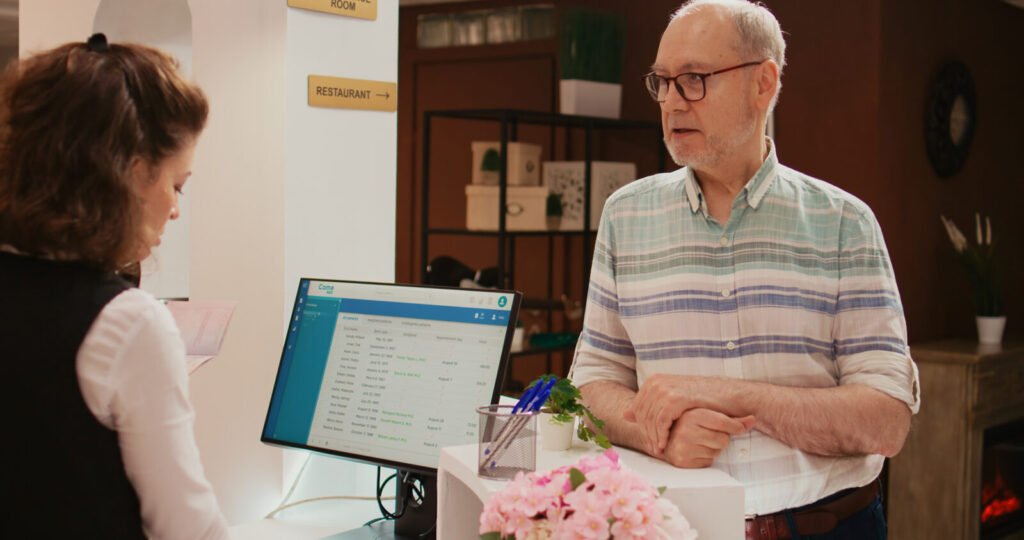 A receptionist checking an older patient in at a clinic front desk