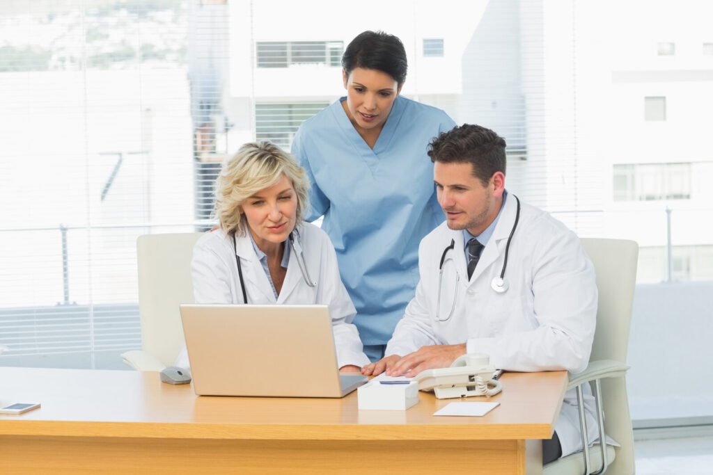 Three clinicians reviewing information together on a laptop