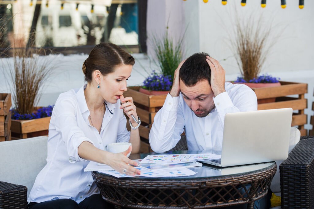 Two people looking over paperwork at an outdoor table with concern