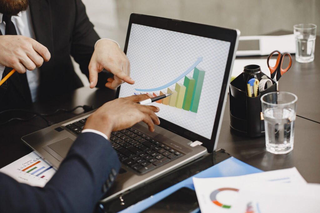 Two people pointing at a revenue chart on a laptop screen