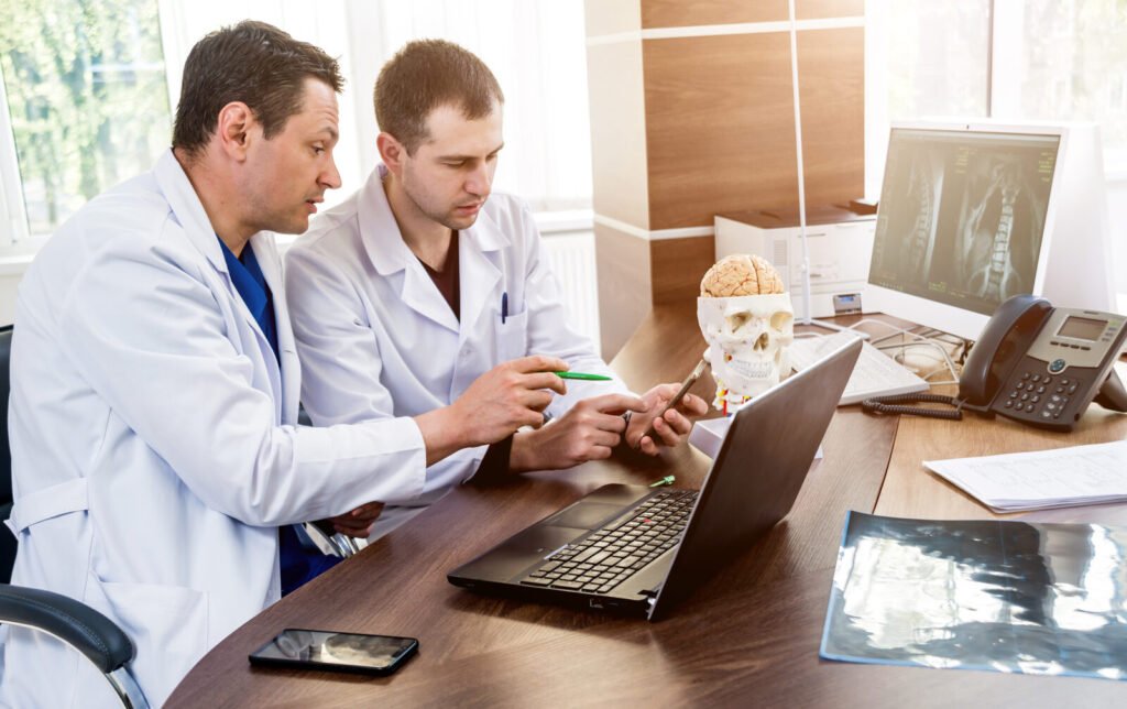 Two clinicians reviewing imaging and notes together at a laptop