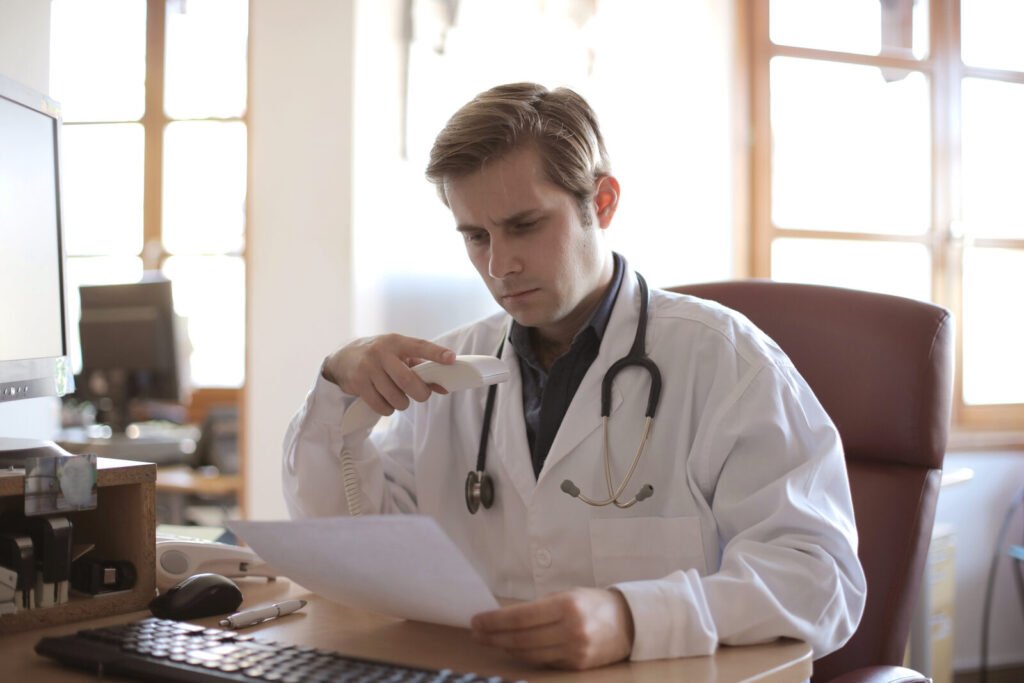 A physician reading a printed remittance beside a keyboard