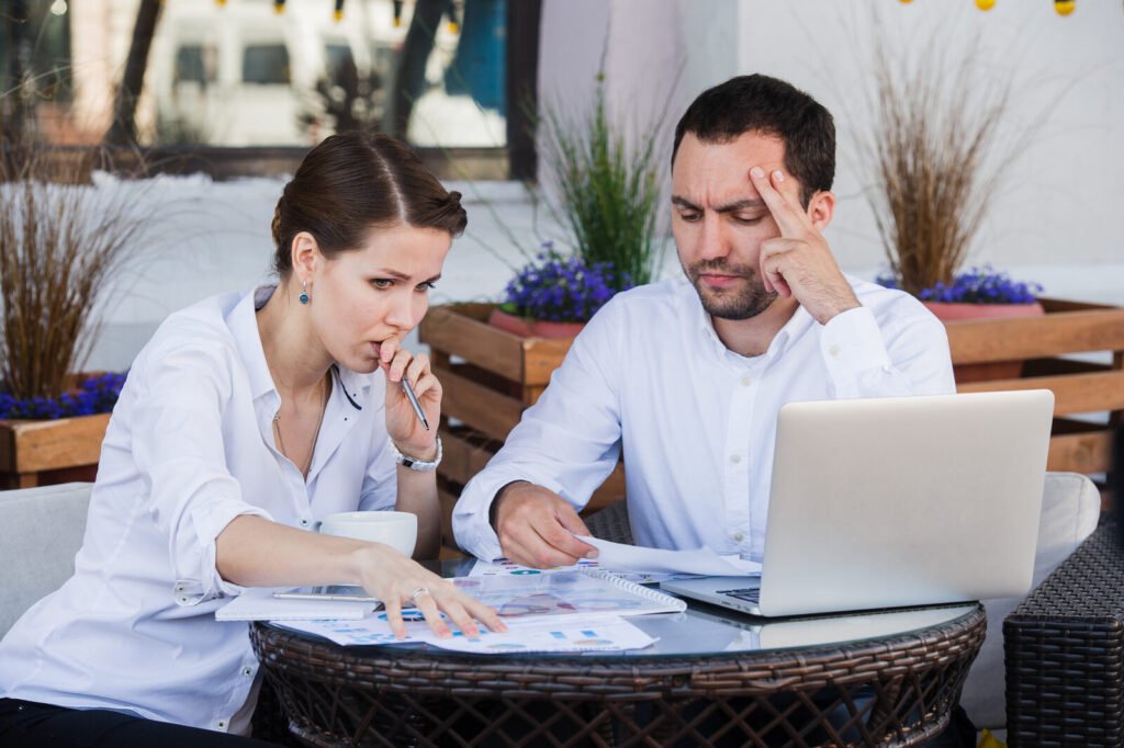 Two people reviewing a statement at a laptop with concern