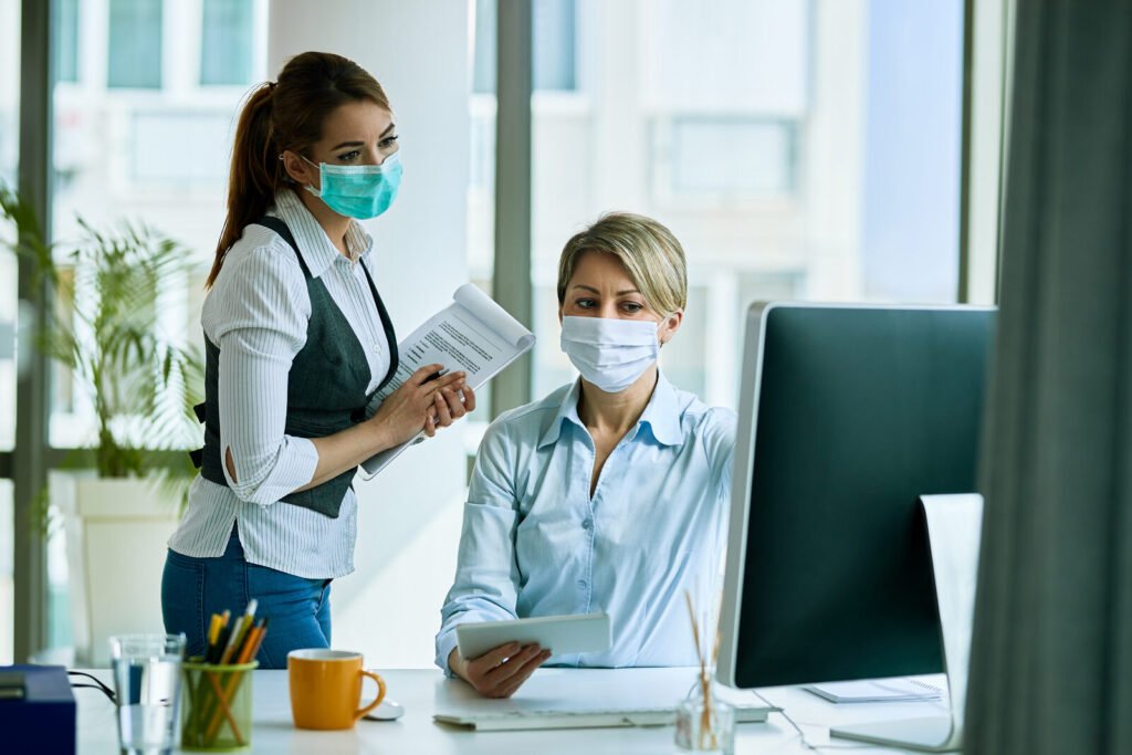 Two masked staff members working together at a front-office computer