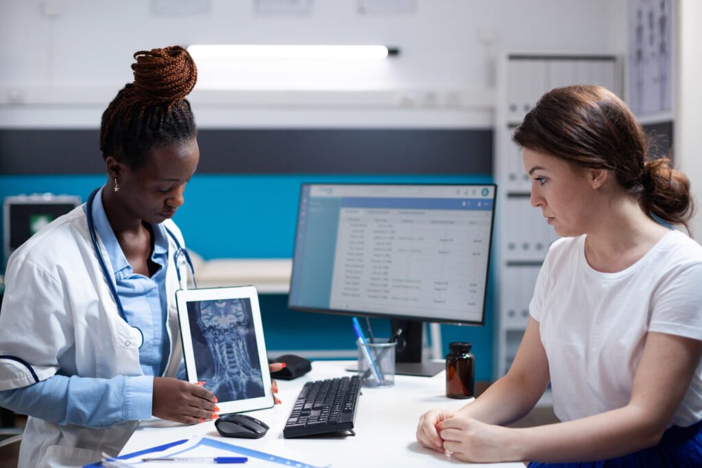 A clinician showing imaging on a tablet to a patient across a desk