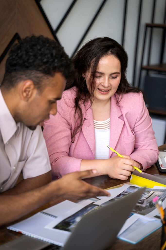 Two colleagues reviewing documents and a laptop together at a table