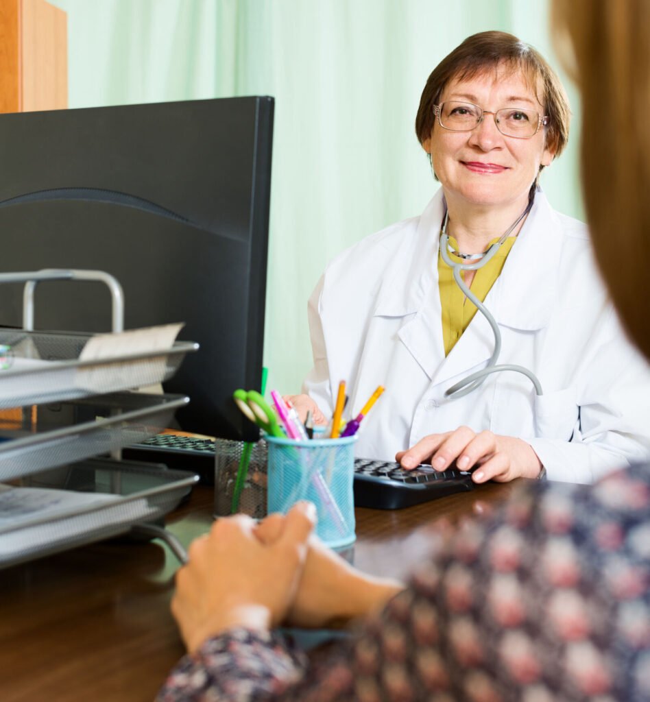 A smiling physician at her desk talking with a patient