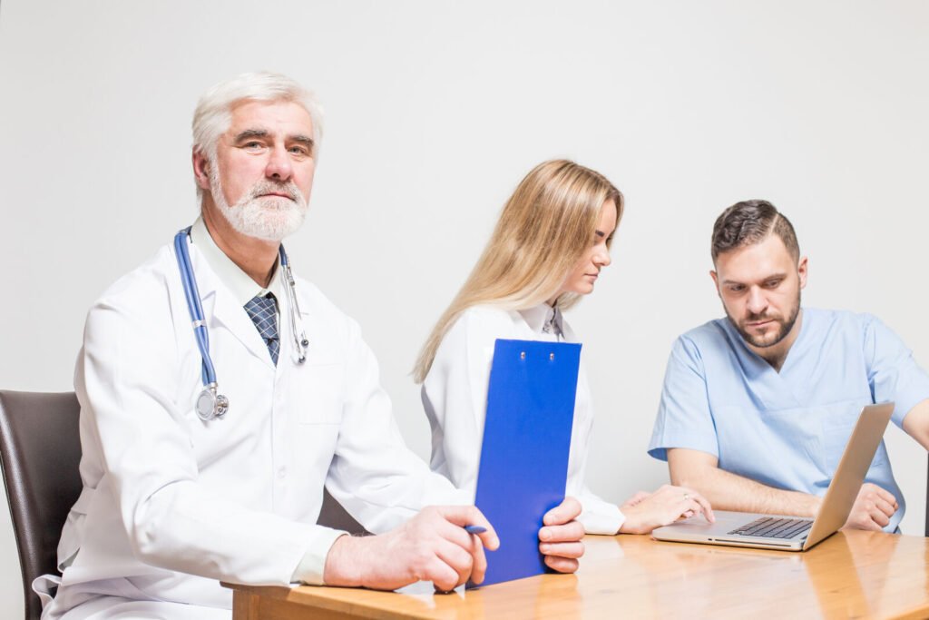 A physician and two colleagues reviewing files together at a desk