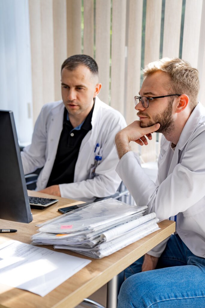 Two physicians reviewing claim paperwork at a computer