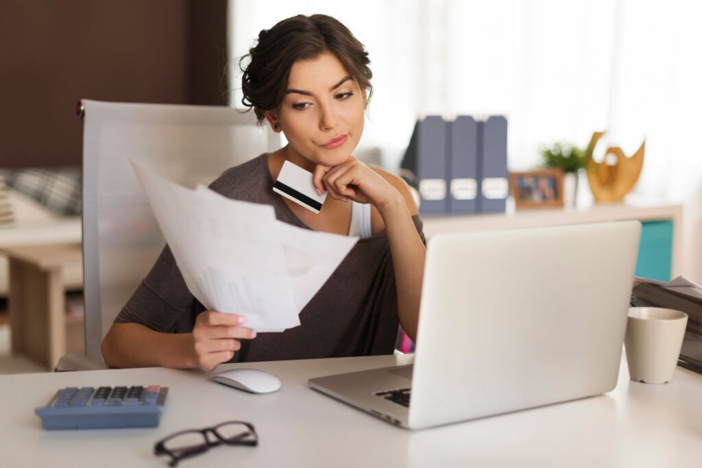 A billing specialist studying a payer statement at a desk beside a laptop
