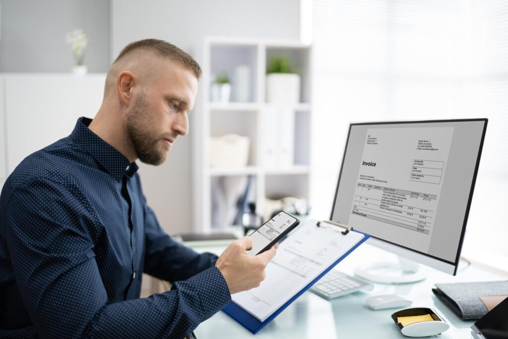 A billing specialist holding a clipboard while checking a claim on a computer screen