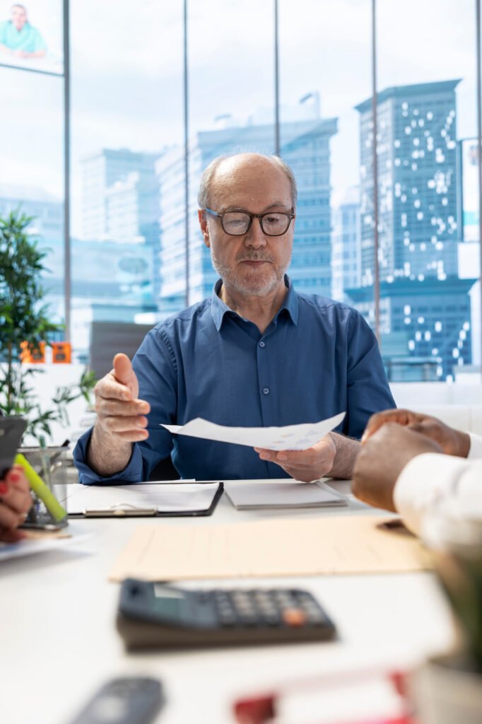 A man in glasses reviewing payer paperwork at a desk with a calculator