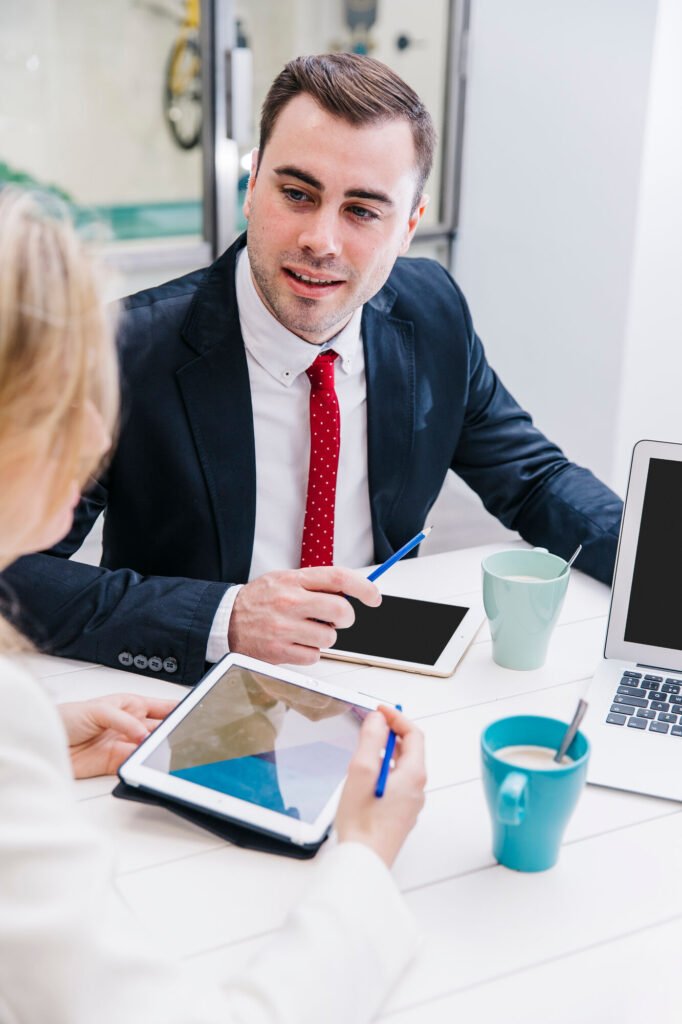 A consultant going over enrollment details with a client at a desk